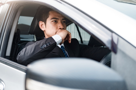 Driver, Confident young businessman sitting on the front seat and smiling while driving a car.
