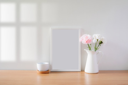 Mock up protrait photo frame with flowers on table, home decoration.