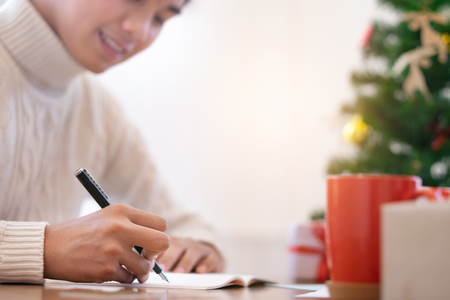 Christmas  concept.  Man wearing white sweater writing greeting cards.の写真素材