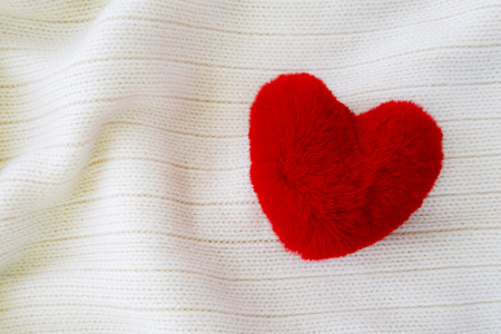 Fluffy red heart on white soft cozy fabric background. Handmade pretty heart. Love, romance,...