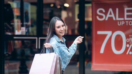 Exciting woman in shopping pointing to sale board. Consumerism, shopping, lifestyle concept.の写真素材