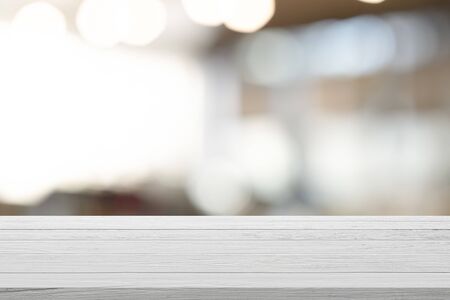 Empty wooden table for present product on coffee shop or soft drink bar blur background with bokeh image.の写真素材