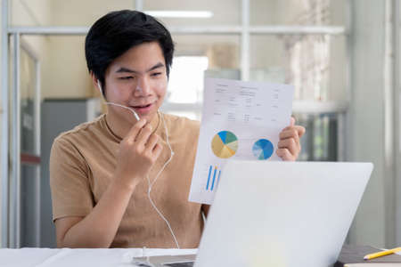 Online meeting and working at home or office. Happy young man speaking looking and using laptop for video conference.の写真素材