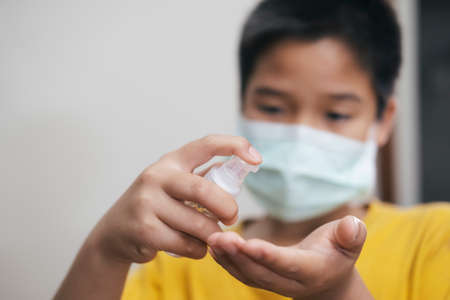 COVID-19, Close up boy using bottle of antibacterial wash hand sanitizer gel dispenser, against Novel coronavirus (2019-nCoV) at home.  Home isolation and Healthcare concept.の写真素材