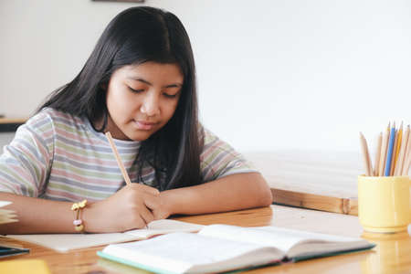 Elementary school pupil is self studying and doing homework at home. Education and distance learning...