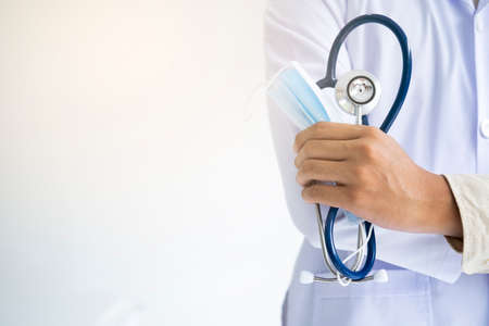 Young man doctor holding stethoscope and medical mask to protect against coronavirus 2019 disease or COVID-19 global outbreak.の写真素材