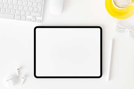 Top view of blank screen tablet on white working desk background.