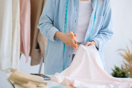 Fashion designer working in studio, cutting drawing, sewing dress