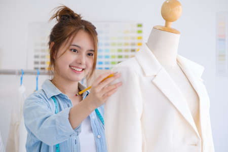 Fashion designer working in studio, cutting drawing, sewing dress