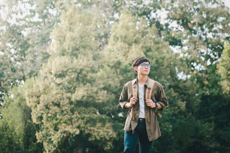 Young man walking with backpacks over natural background.
