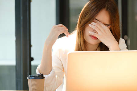 Tired frustrated young employee woman working at laptop computer too long, overworking in office,...