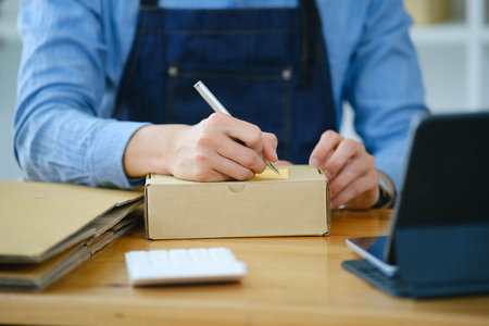 Start up small business owner writing address on cardboard box a.の写真素材