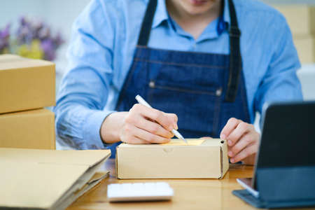 Start up small business owner writing address on cardboard box a.の写真素材