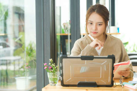 Young female college student uses a computer to access the Internet for online learning.の写真素材