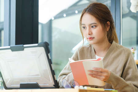 Young female college student uses a computer to access the Internet for online learning.