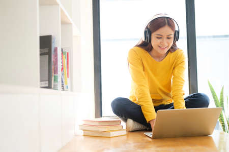 Young collage student using computer and mobile device studying online.