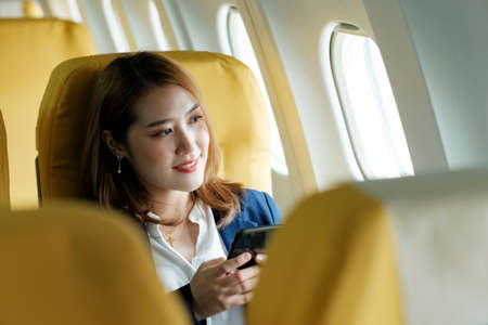 Business woman In a plane, works on using on phone.