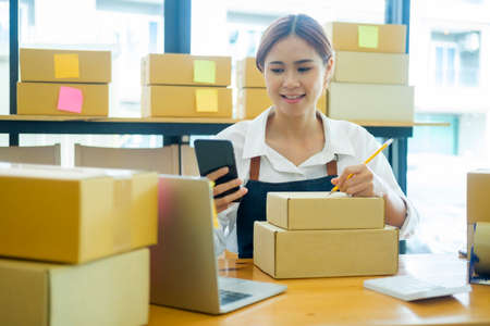 Start up small business owner writing address on cardboard box a.