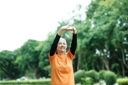 Athletic Senior woman stretching arms in park.の写真素材