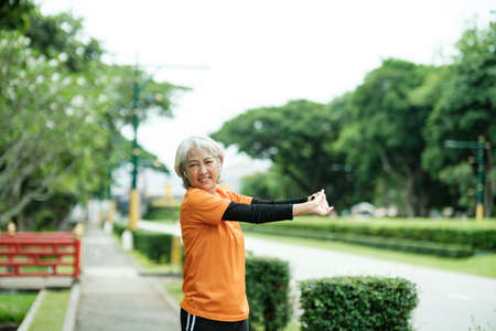 Athletic Senior woman stretching arms in park.の写真素材