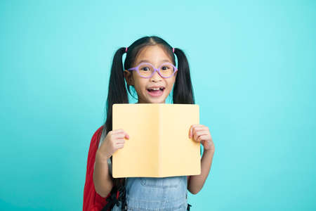 Close-up kid students girl smiling holding book, going to school.の写真素材