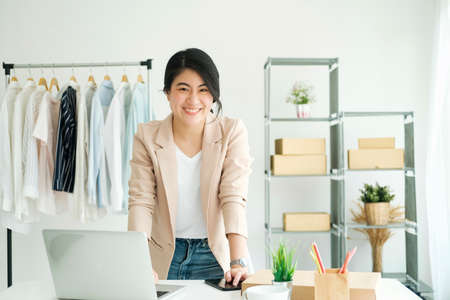 Happy young asian female freelan standing in online clothing store.の写真素材