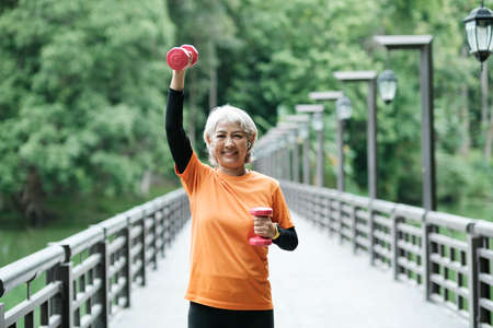 Athletic Senior woman lifts dumbbells while doing fitness.の写真素材