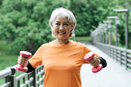 Athletic Senior woman lifts dumbbells while doing fitness.の写真素材