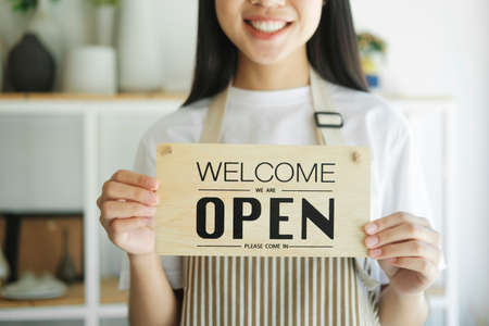 Young asian business owner turning open sign product store and ready to service for welcome the...