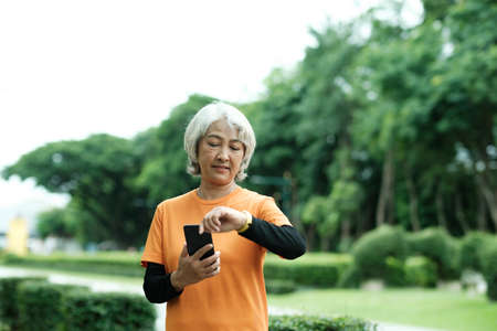 Happy athletic Senior woman checking her smartwatch in the parkの写真素材