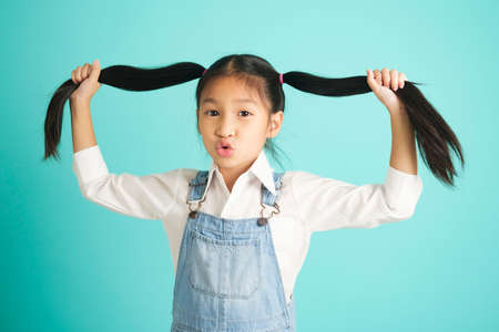 Smiling little girl in glasses pretty long hair, hold hair above her , look at camera.の写真素材
