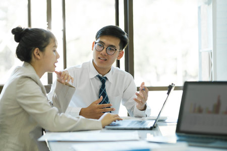 Businesspeople or office workers are working together on investment project. They are discussing, sharing the ideas, planning, and analyzing the business strategy. And set up the budget for financial plan by using laptop and calculator.の写真素材