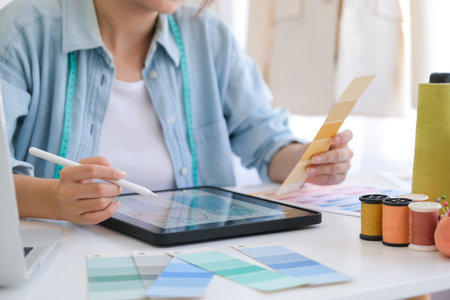 A young asian female fashion designer designing the fashion collection on tablet.の写真素材