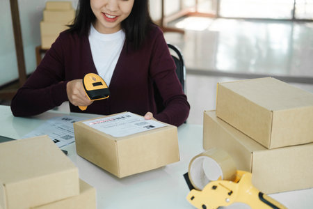Female online business owner scan shipping label on parcel.