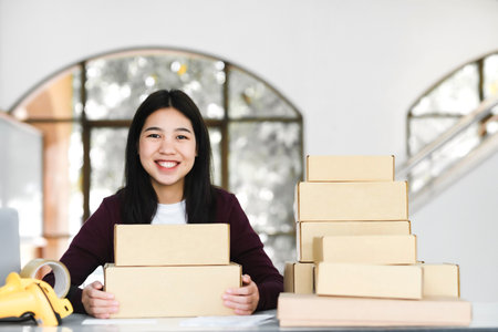 Female online business owner holding parcel and looking at camera.の写真素材