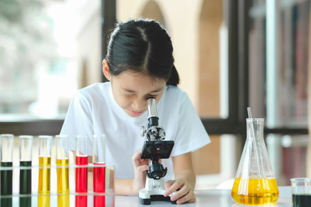 Little child with learning class in school laboratory using microscopeの写真素材