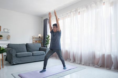 Active mature woman doing stretching exercise in living room at home.の写真素材