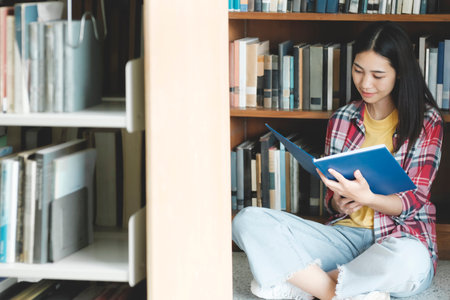 University students reading books in library for research.の写真素材