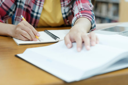 Close up hands with pen writing on notebook.