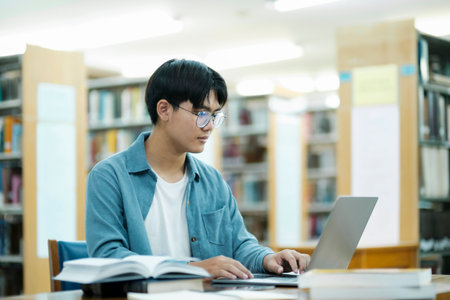 Young university student using laptop for online learning, searching and learning at library.の写真素材