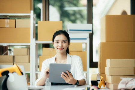 Young business woman working online e-commerce shopping at her shop.の写真素材
