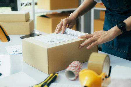 Young business owner putting shipping label on parcel..の写真素材