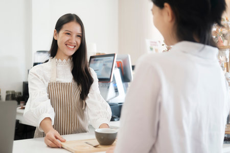 Smiling friendly barista serving a cup of coffe to customer at coffee shop.