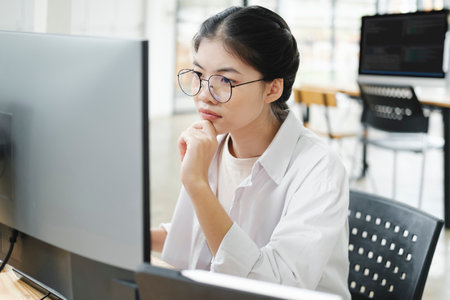 Young programmer working on desktop PC in office of software company.の写真素材