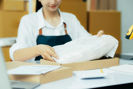 Small business owner packing clothes in the box at workplace.の写真素材