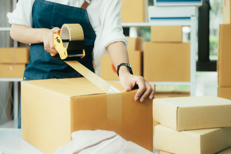 Online entrepreneur using  tape to seal parcel box.