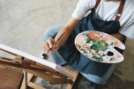 Young Asian female artist painting on canvas doing art projects on her studio.の写真素材