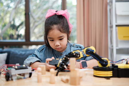 A young girl is playing with a remote control a robotの写真素材