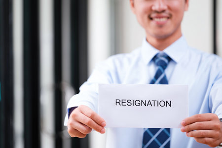 Confident Man Holding Up Resignation Letter with a Smile, Signaling a Positive Transition and Optimistic Outlook on Future Endeavorsの写真素材