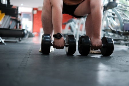 A man is lifting three dumbbells in a gymの写真素材
